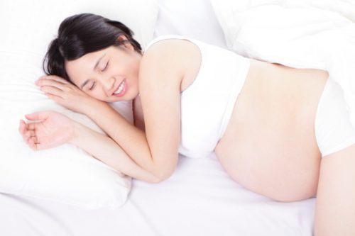 Pregnant woman smile lying on the bed