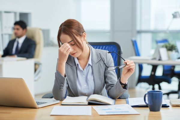 medium shot young asian woman sitting desk office rubbing nose min