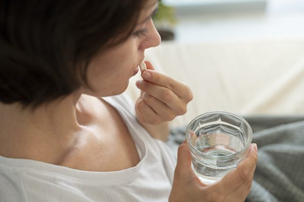 close up woman taking pill min